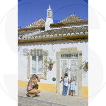 Woman takes picture of kids in front of traditional Algarvian house