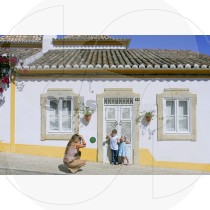 Woman takes picture of kids in front of traditional Algarvian house