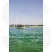Fishing boat in Ria Formosa with coast and mountains in background